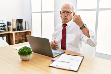 Ofiste çalışan son sınıf öğrencisi bilgisayar kullanıyor. Kol kası gösteren güçlü, kendinden emin ve gururlu biri. 