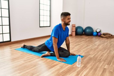 Yakışıklı İspanyol adam egzersiz yapıyor ve yoga minderinde geriniyor. Spor salonunda esneklik ve antrenman yapıyor.