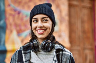 Genç İspanyol kadın şehirde kulaklık takarak mutlu gülümsüyor..