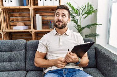 Yakışıklı İspanyol bir adam pano tutuyor psikoloji kliniğinde çalışıyor gülümsüyor ve başka tarafa bakıyor.. 