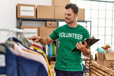 Gönüllü olarak üniforma giyen İspanyol genç bir adam yardım merkezinde kıyafet arıyor.