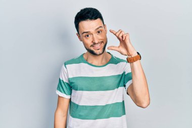 Gündelik kıyafetler giyen, gülümseyen, kendine güvenen, el hareketi yapan, parmaklarıyla işaret yapan ve kameraya bakan genç İspanyol bir adam. ölçüm kavramı. 