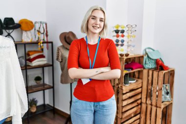 Perakende mağazasında yönetici olarak çalışan beyaz bir kadın kollarını kavuşturup kameraya bakarak gülümsüyor. pozitif kişi. 