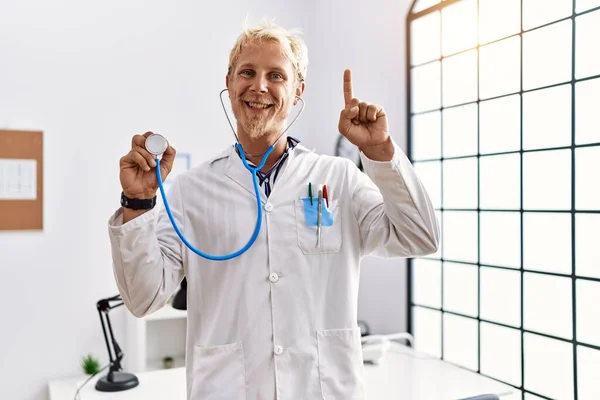 Młody Blondyn Mundurze Lekarza Trzymający Stetoskop Klinice Zaskoczony Pomysłem Lub — Zdjęcie stockowe