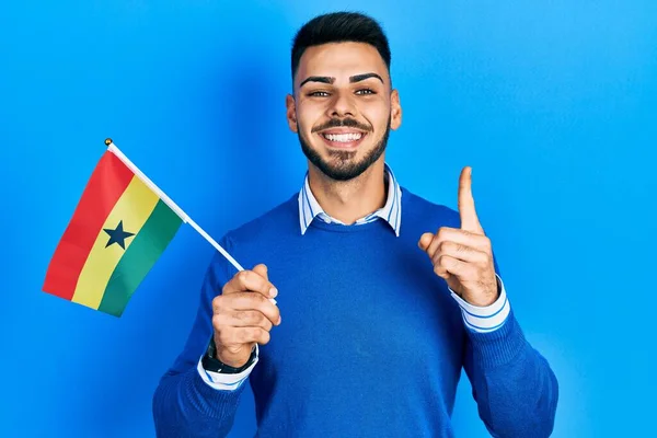Joven Hispano Con Barba Sosteniendo Bandera Ghana Sonriendo Con Una —  Fotos de Stock