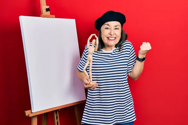 Middle Age Hispanic Woman Standing Painter Easel Stand Holding Manikin — Stock Photo, Image