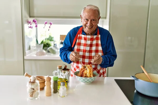 Senior Άνθρωπος Χαμογελά Αυτοπεποίθηση Ανάμειξη Σάλτσα Ντομάτας Μακαρόνια Στην Κουζίνα — Φωτογραφία Αρχείου