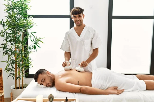 Due Uomini Ispanici Fisioterapista Paziente Massaggiare Indietro Utilizzando Borse Tailandesi — Foto Stock