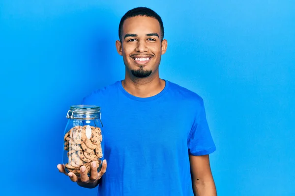 Joven Hombre Afroamericano Sosteniendo Tarro Galletas Chocolate Con Aspecto Positivo — Foto de Stock