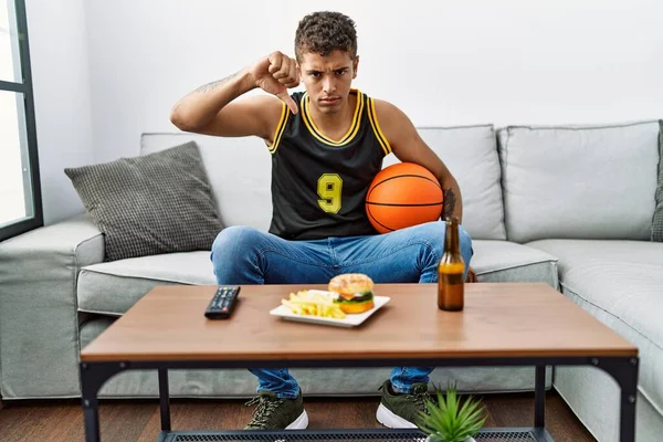 Молодой Красивый Латиноамериканец Держащий Баскетбольный Мяч Аплодирующий Телеигре Сердитым Лицом — стоковое фото