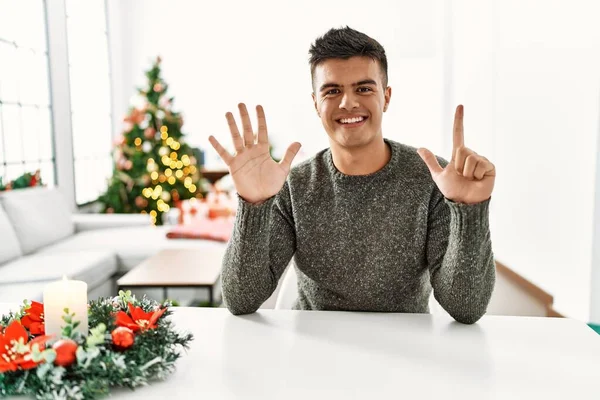Young Hispanic Man Sitting Table Christmas Tree Showing Pointing Fingers — 스톡 사진