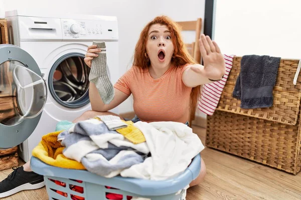 若い赤毛の女性は手の手のひらで停止ジェスチャーを行う洗濯機に汚れた洗濯機を入れて 怒っているとフラストレーション式 — ストック写真