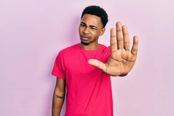 若いアフリカ系アメリカ人の男性は 手の手のひらで歌うのをやめるカスアキャストシャツを着ている 顔に負の重大なジェスチャーで — ストック写真