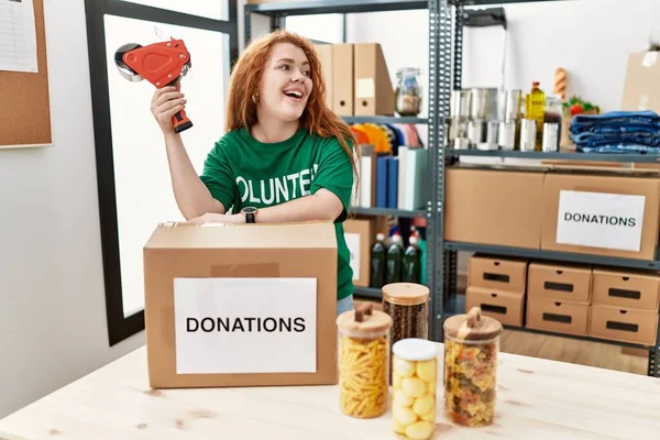 Mujer Pelirroja Joven Con Uniforme Voluntario Embalaje Caja Donaciones Centro — Foto de Stock