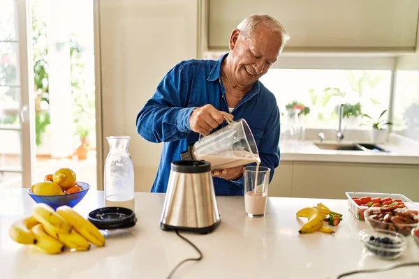 Hombre Mayor Sonriendo Confiado Vertiendo Batido Sobre Vidrio Cocina —  Fotos de Stock