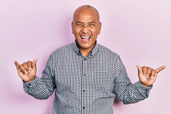 Orta yaşlı, gündelik kıyafetler giymiş çılgın bir ifadeyle bağıran, elleri havada rock sembolü yapan Latin bir adam. Müzik yıldızı. ağır kavram. 