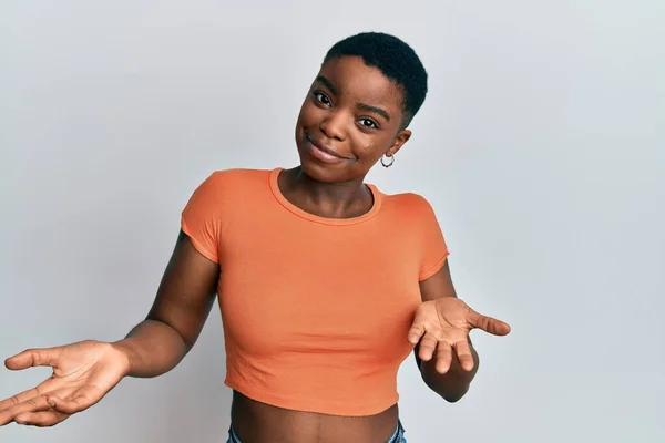 年轻的非洲裔美国女人穿着休闲的橙色T恤 毫无头绪 满脸困惑 手臂和双手高举 怀疑概念 — 图库照片