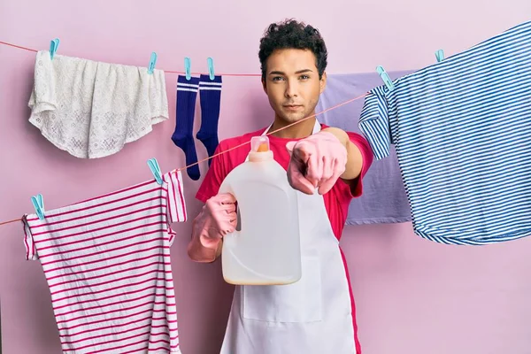 Hombre Hispano Guapo Lavando Ropa Sosteniendo Botella Detergente Señalando Con — Foto de Stock