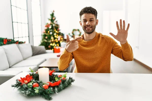 Arab Young Man Sitting Table Christmas Tree Showing Pointing Fingers — 스톡 사진