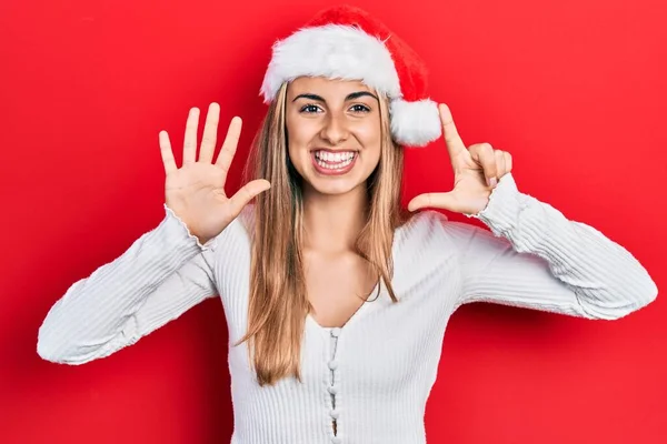 Красивая Латиноамериканка Рождественской Шляпе Показывает Показывает Пальцами Номер Семь Улыбаясь — стоковое фото