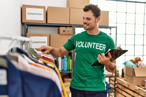 Gönüllü olarak üniforma giyen İspanyol genç bir adam yardım merkezinde kıyafet arıyor.