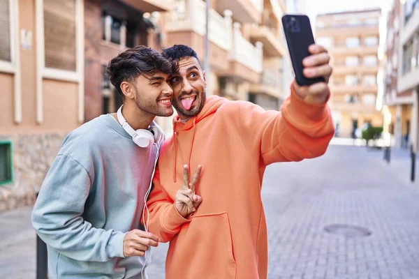 Sokakta akıllı telefondan selfie çeken iki erkek.