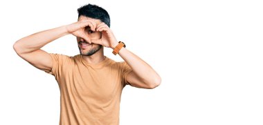 Sakallı, sıradan tişörtlü, kalp şeklinde elleri ve parmakları olan İspanyol bir adam tabeladan bakıp gülümsüyor. 