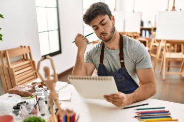Resim stüdyosunda ciddi yüz ifadesi olan genç bir İspanyol ressam..