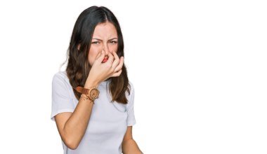 Gündelik beyaz tişört giyen genç, güzel bir kadın pis ve iğrenç bir koku alıyor. Nefesini burnunda tutuyor. Kötü kokuyor. 