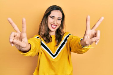 Gündelik kıyafetler giyen, dili açık gülümseyen, zafer işareti yapan genç İspanyol kız. İki numara.. 