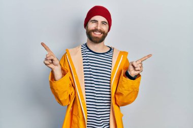 Sakallı, sarı yağmurluk giyen, kendine güvenen, farklı yönleri gösteren beyaz bir adam. reklam için kopyalama alanı 