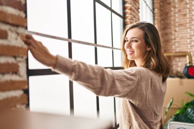 Young woman smiling confident measuring window at new home