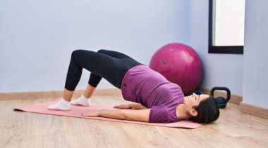 Spor merkezinde karın kaslarını çalıştıran genç bir kadın.