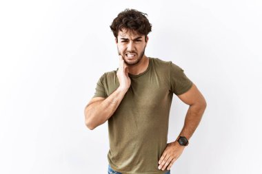 İzole edilmiş beyaz arka planda duran İspanyol bir adam diş ağrısı ya da diş hastalığından dolayı acı dolu bir ifadeyle ağıza dokunuyor. dişçi 