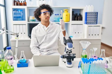 Laboratuvarda kan testi tüpü analizi yapan bilim adamı üniforması giyen genç bir İspanyol.