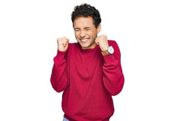 Başarılı olmak için heyecanlı, kolları havada ve gözleri kapalı gülümseyerek zaferi kutlayan gündelik giysiler giyen genç yakışıklı bir adam. Kazanan konsept. 