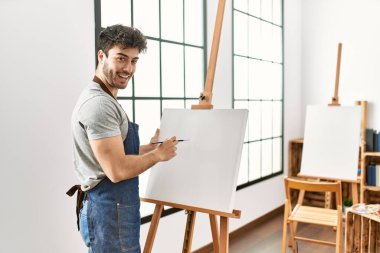 Resim stüdyosunda gülümseyen genç İspanyol ressam..
