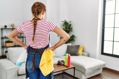 Arkadan bakan genç bir kadın evde dikiliyor.