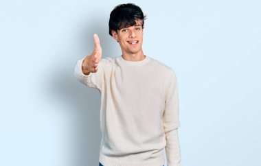 Yakışıklı hippi genç adam sıradan bir süveter giyer dostça gülümseyerek selamlaşır ve hoş geldin der. başarılı iş. 