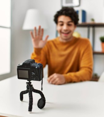 Evdeki kanepede oturan Latin asıllı genç bir adam kamerayla görüntülü görüşme yapıyor..