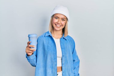 Güzel sarışın kadın bir fincan kahve içiyor. Pozitif ve mutlu görünüyor. Kendine güvenen bir gülümsemeyle dişlerini gösteriyor. 