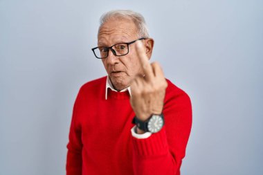 Senior man with grey hair standing over isolated background showing middle finger, impolite and rude fuck off expression 