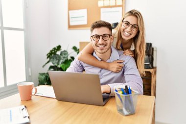 Ofiste çalışırken gülümseyen ve sarılan iki iş adamı..