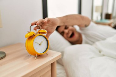 Genç İspanyol adam yatak odasında yatarken çalar saati kapatıyor..