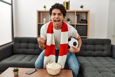 Genç İspanyol adam futbol maçı izliyor ve takımını evde destekliyor..