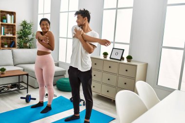 Genç Latin sporcu çift gülümseyerek evde mutlu bir antrenman yapıyor..