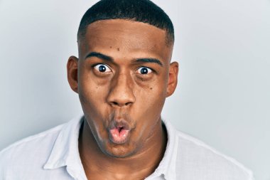 Young black man over isolated background scared and amazed with open mouth for surprise, disbelief face 