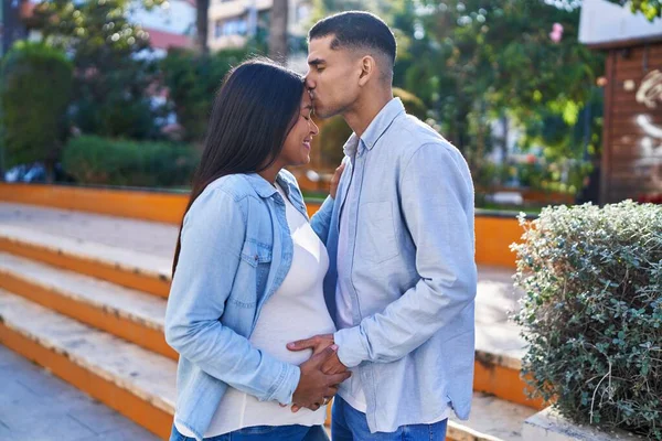 Young Latin Couple Expecting Baby Touching Belly Kissing Park — Stock fotografie
