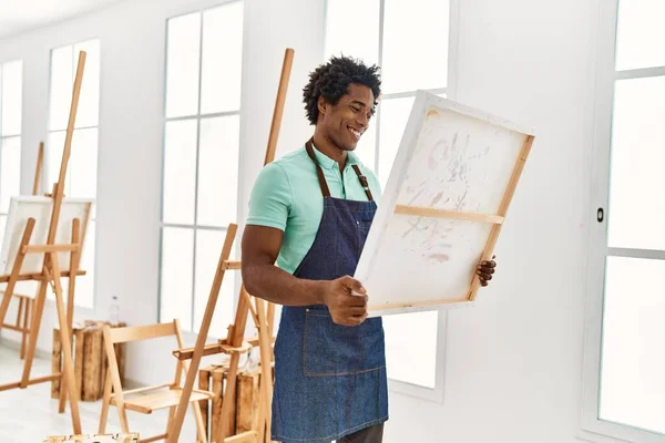 年轻的非洲裔美国艺术家在艺术工作室拿着画布开心地笑着 — 图库照片
