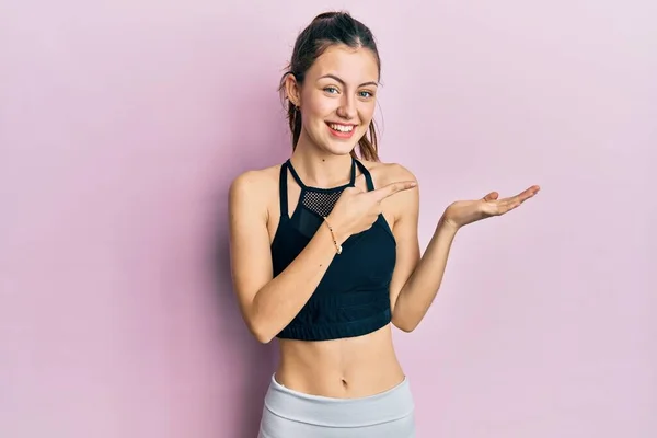 Young Brunette Woman Wearing Sportswear Amazed Smiling Camera While Presenting — Zdjęcie stockowe